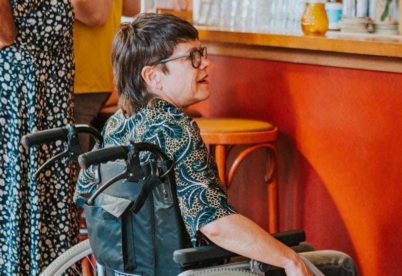 Foto van twee personen in een rolstoel bij de bar